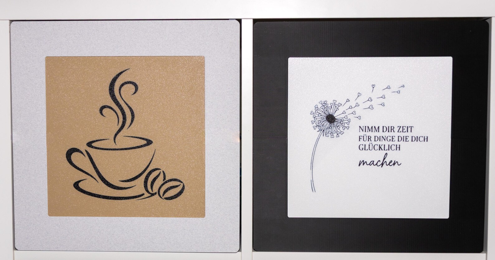 Zwei KALLAX Rahmen mit Inlays: Kaffeemotiv in Gold und Schwarz sowie Pusteblume mit Zitat in Weiß und Schwarz